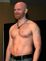 John on stage in grey leather jeans and a bare chest