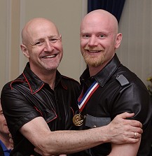 Colour photo of Dave and John, hugging each other and looking delighted